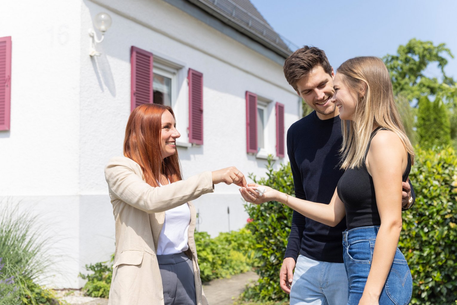 Immobilienmaklerin übergibt jungem Paar Hausschlüssel