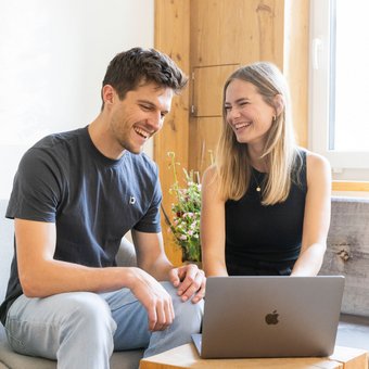 Junges Paar sitzt vor Laptop und sieht sich Häuser an